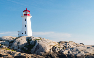 A red and white lighthouse on top of a rocky shore.