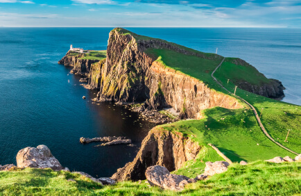 Rocky sea cliffs with green grass covering the tops.